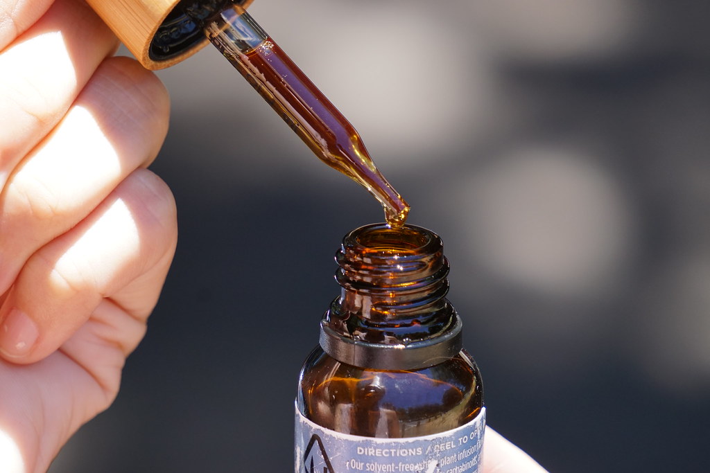 Dropper drawing amber oil from a small tincture bottle