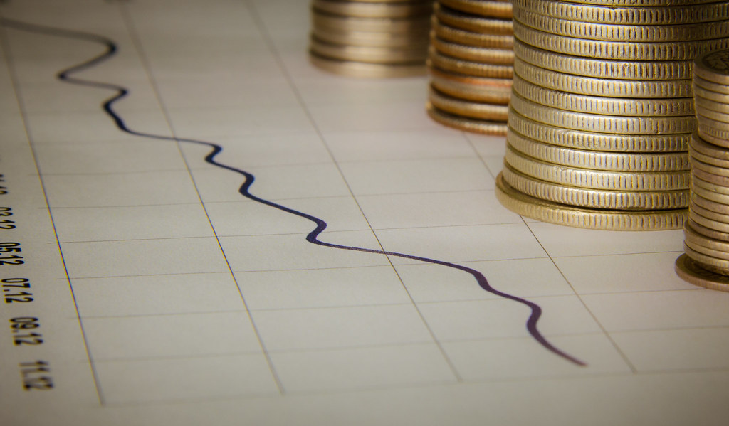 Stacks of coins beside a line chart printed on graph paper